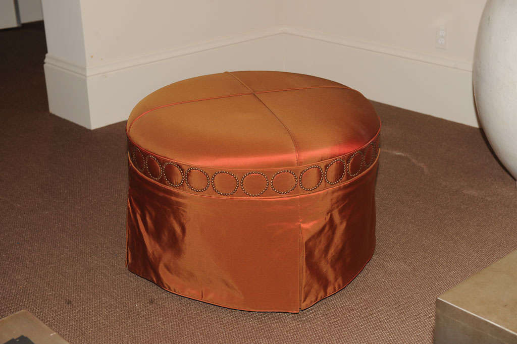 Candace Barnes Now ' Osiris ' Round Ottoman with Cross Welt detailing on Top, Above Circular Nailhead Application and Pleated Skirt.<br />
<br />
finish options: chrome or antique bronze nailhead detail<br />
 ~ lead time 10 - 12 weeks ~<br
