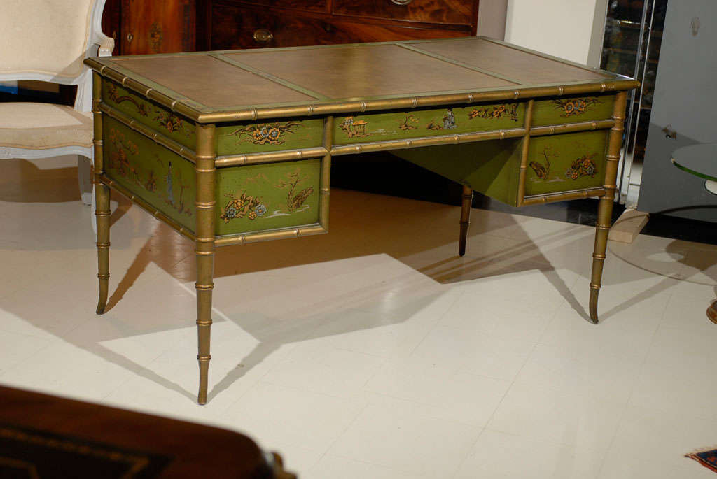 Unique green color faux bamboo chinoiserie vintage desk with embossed leather top over a frieze fitted with three drawers with campaign style handles, supported by two drawers on either side, standing on faux bamboo tapered feet.