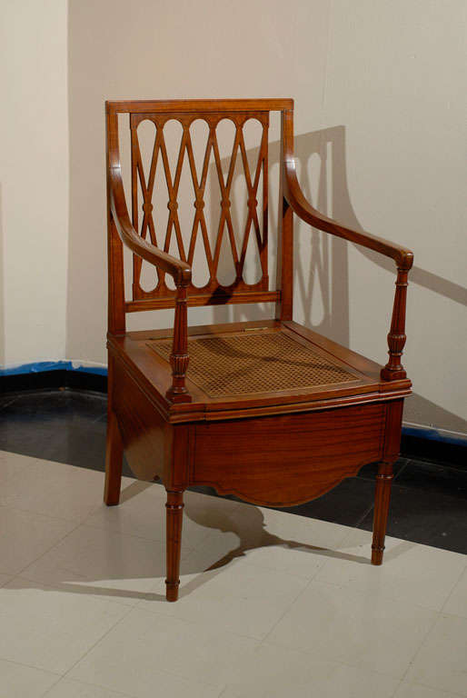 19th c. Sheraton style mahogany potty chair. Ebony stringing outlining entire piece. The back is rectangular with a lattice back and rosette inlays at the crossings. Elegantly curved arms tapering to fluted and turned supports. Caned lift top seat.