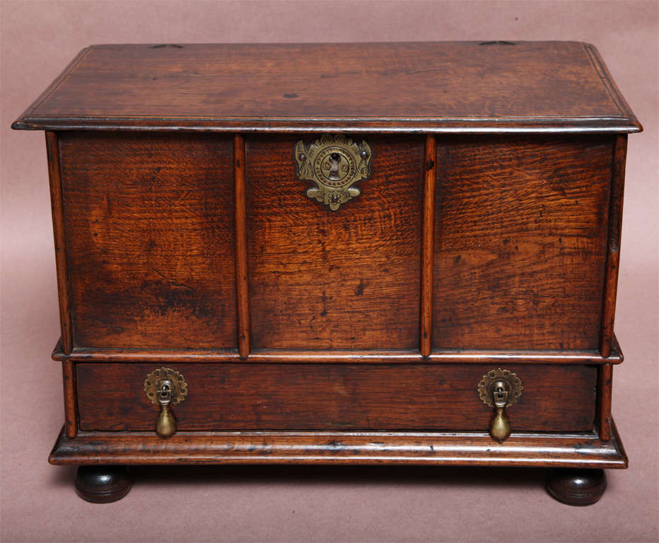 A very rare and desirable 17th century English oak box having moulded front and sides, original lock plate, drop pulls and bun feet, with superb color and patination. The box is made in the form of an English lidded coffer and was made to keep