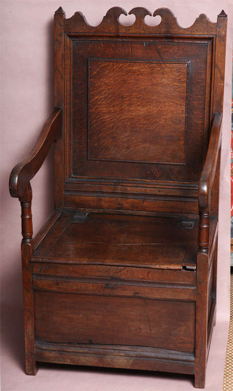 Fine late 17th Century English oak wainscot chair, the shaped crest with wave and scalloping, the back a heavily molded panel, the shaped arms over turned supports, the lift top seat enclosing a paneled box, the whole with rich patination.