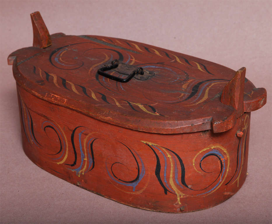 19th century Norwegian painted wood pantry box of typical form, the lid secured by wooden horn springs, the body of fingered bentwood form, decorated in polychrome scrolls.