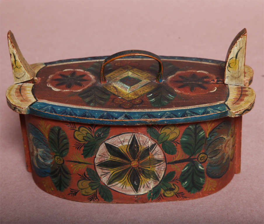 Lovely Norwegian paint decorated oval pantry box, the hid with bent wood handle secured by spring wood horns, the body of bentwood construction, the whole beautifully decorated with floral and geometric patterns and bearing the legend 