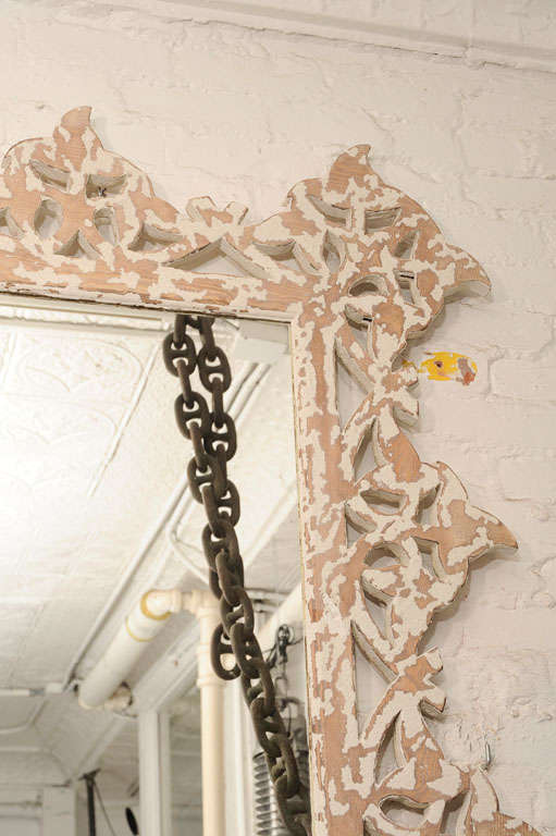 Graceful mirror with a white washed, pierced wood frame.