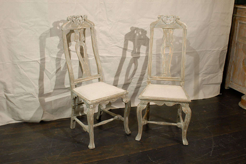 A pair of Swedish 18th century period Baroque painted wood side chairs with tall backs. This pair of Swedish chairs made of fir wood feature a nicely carved top rail, pierced splat and scalloped skirt. The cabriole legs are joined by a cross