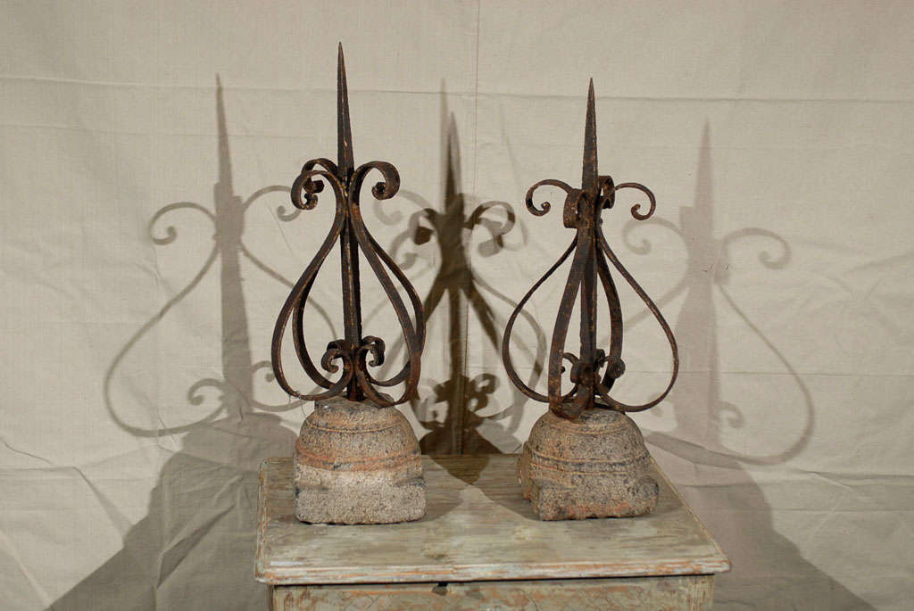 A pair of late 19th century forged iron finials mounted on granite bases. Great patina and general look. The metal part can come off of its base.