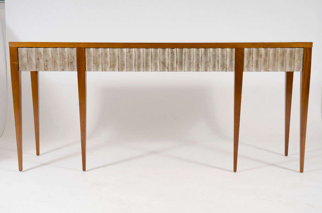 An exquisite companion to our Silver Leaf Fluted Frame Mirror, this console is very long, tall and slender and comprises a simple cherry top with a wide fluted apron finished in silver leaf and conceals three drawers, the whole resting on six square