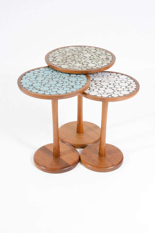A marvelous group of three nesting tables with solid walnut pedestal tulip bases each with complementary colored round ceramic tile tops. By Gordon Martz for Marshall Studios. American, circa 1950.<br />
Dimensions as shown:<br />
12.75