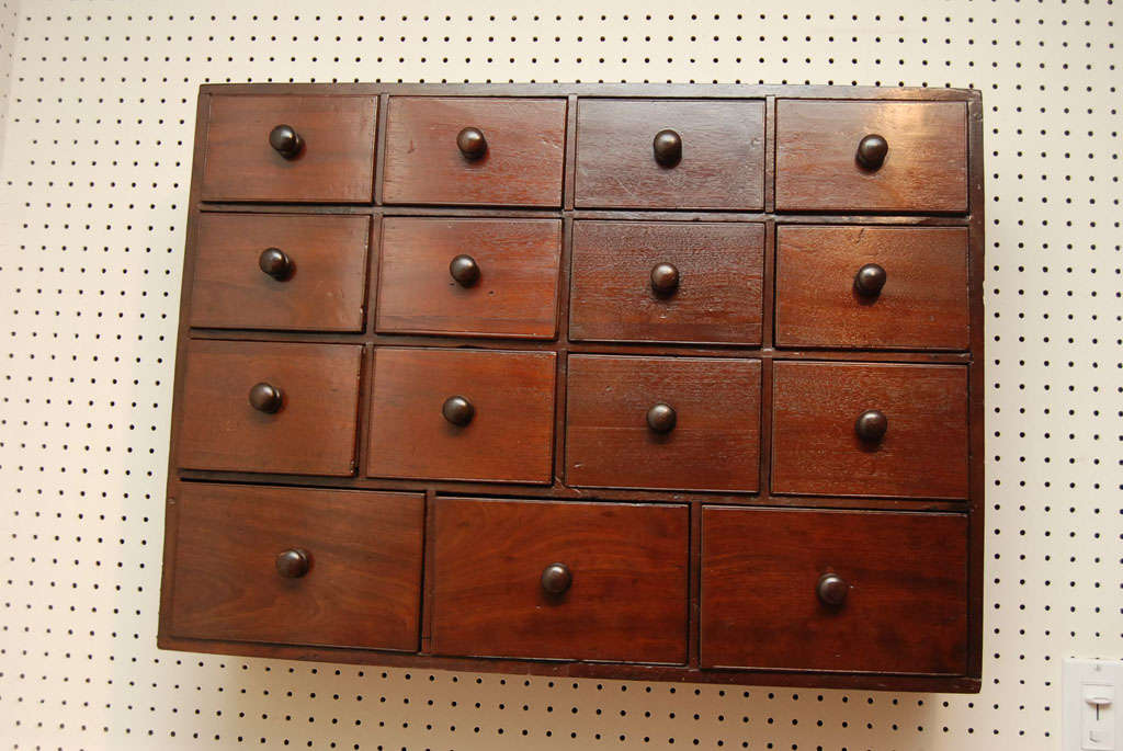This delightful little bank of spice drawers is from France. It has three rows of four small drawers and below them are three larger drawers, all with wood pulls ,in Mahogany.