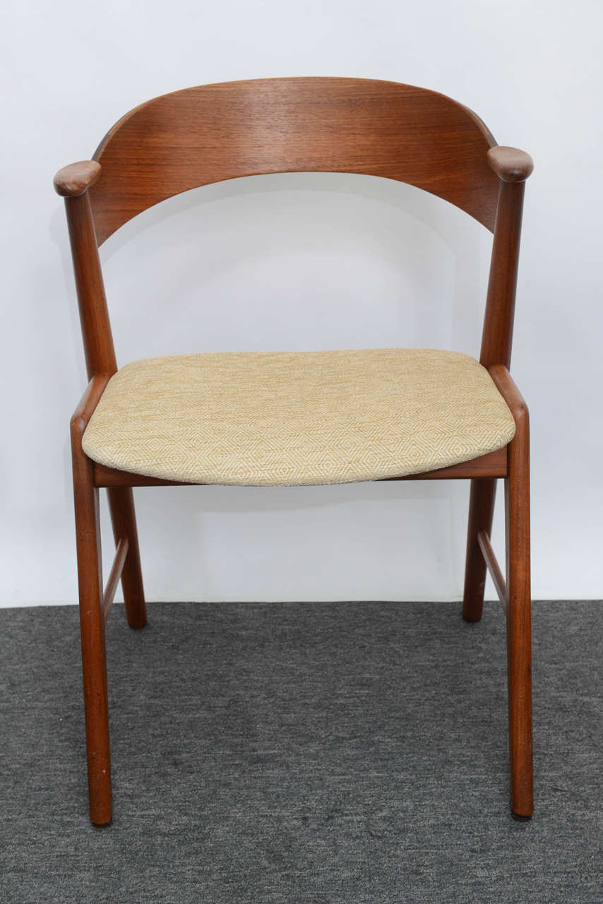 Beautifully designed by Kai Kristiansen in the 1960s, these teak dining chairs feature a curved bent-ply back that flows into the arm rest.  Chair seats are  very comfortable seats and have been freshly upholstered in a high quality beige cotton.