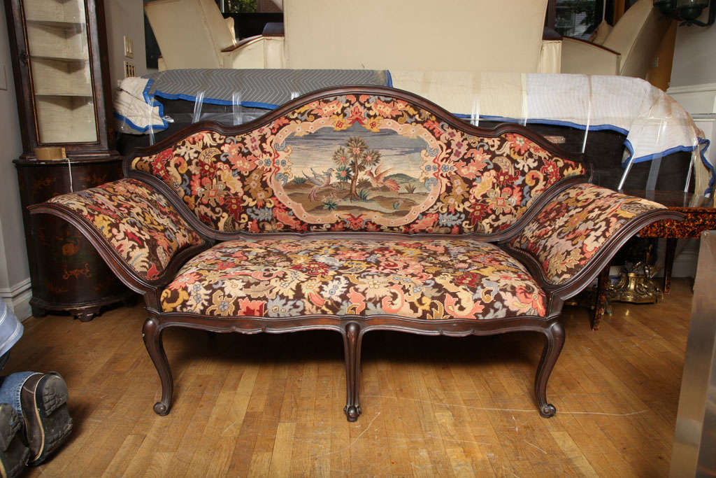 An Italian walnut 2 seat sofa, the arched back seat and sides covered in original needlework with petit point, the back with center reserve depicting landscape with animals. Supported by 6 cabriole legs.