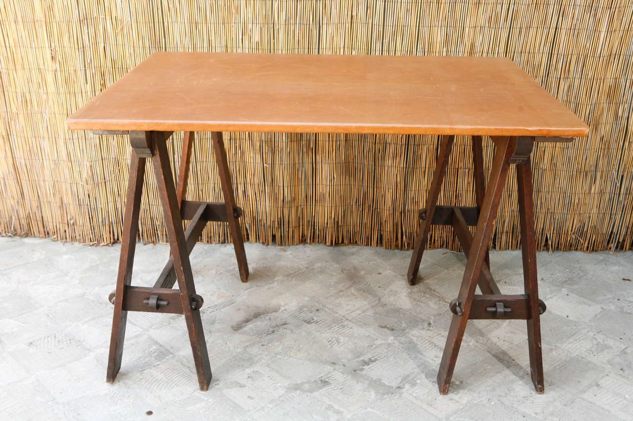 Beautiful leather topped table with hand-pegged sawhorse legs. The top is original but the leather was added at some later point.  It is from the Arts and Crafts period.