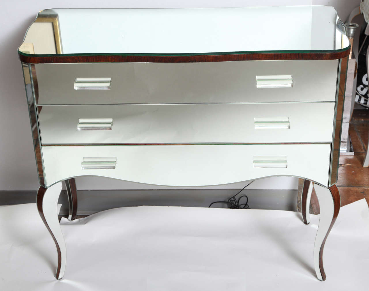 A stylish mirrored commode with glass pulls and cabriole legs.