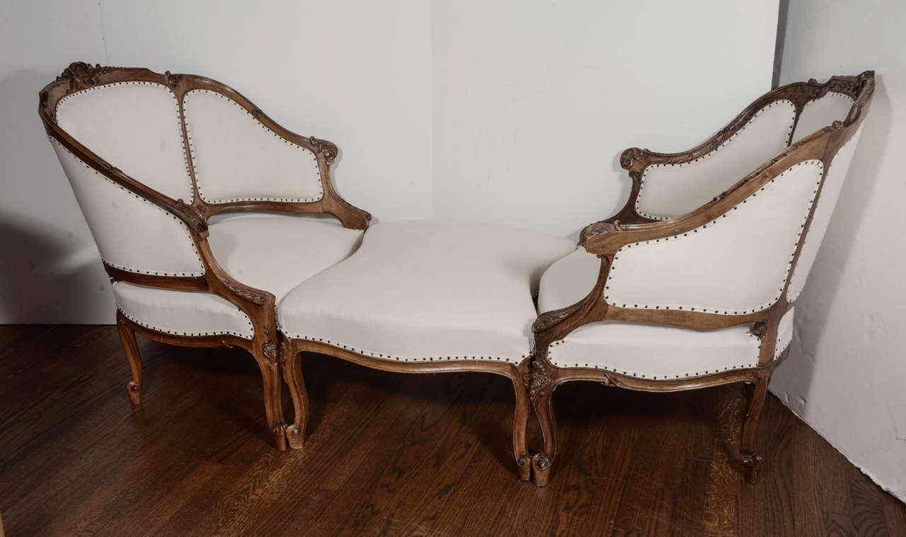 Louis XV style carved mahogany armchairs and ottoman. Three pieces interlock to form a chaise lounge. The chairs are delicately carved with shell motifs and are 