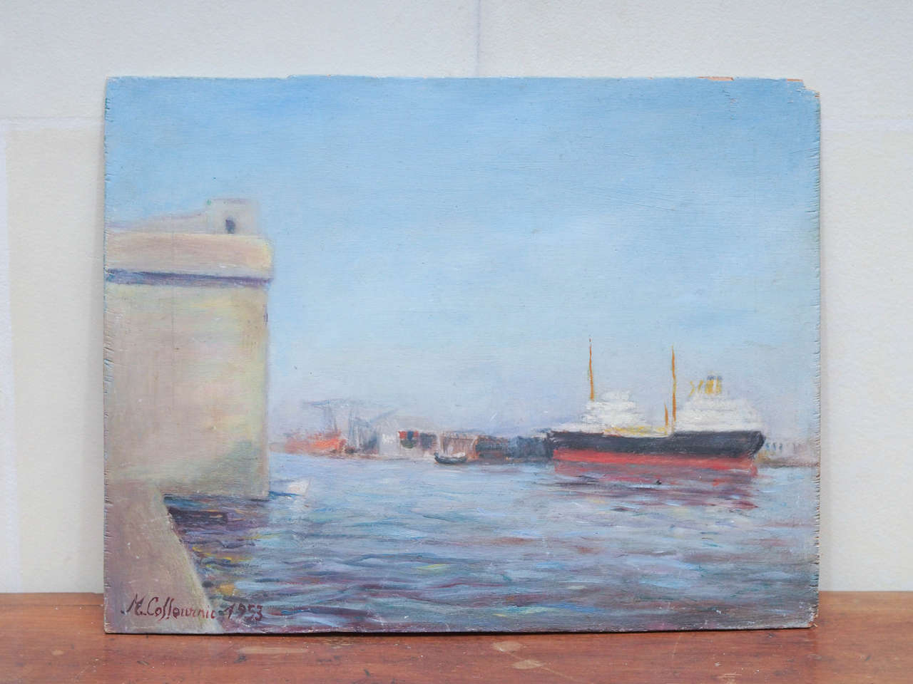 Signed on the reverse M. Colloivinic Dec '53, this oil on board painting is of Saint-Nazaire. Saint-Nazaire is a Community on the Loire-Atlantic department in western France, in traditional Brittany. The town has a major harbor on the right bank of