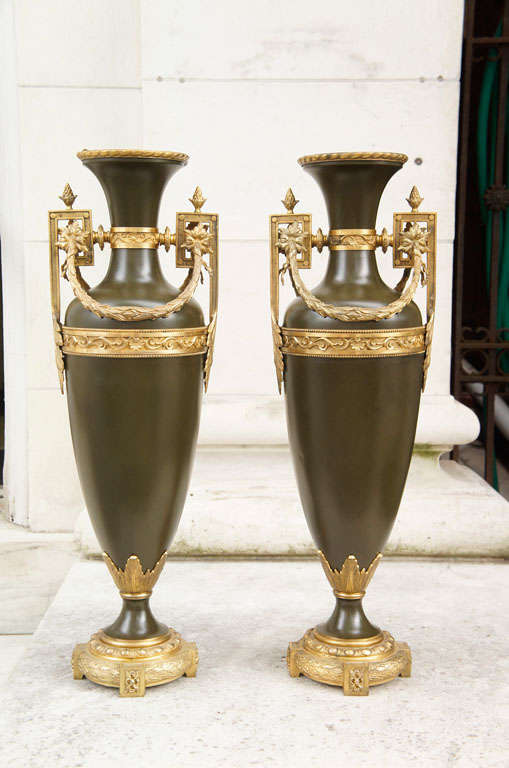 This large pair of urns have tole bodies painted to resemble patinated bronze and then trimmed in gilded bronze. In addition to being used as prominent  decorative elements in an interior, the can also be used as flower vases as they have liners
