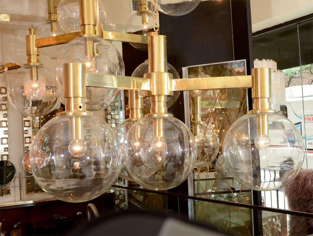 Brass three-arm spoke form chandelier with four large clear glass spherical shades.