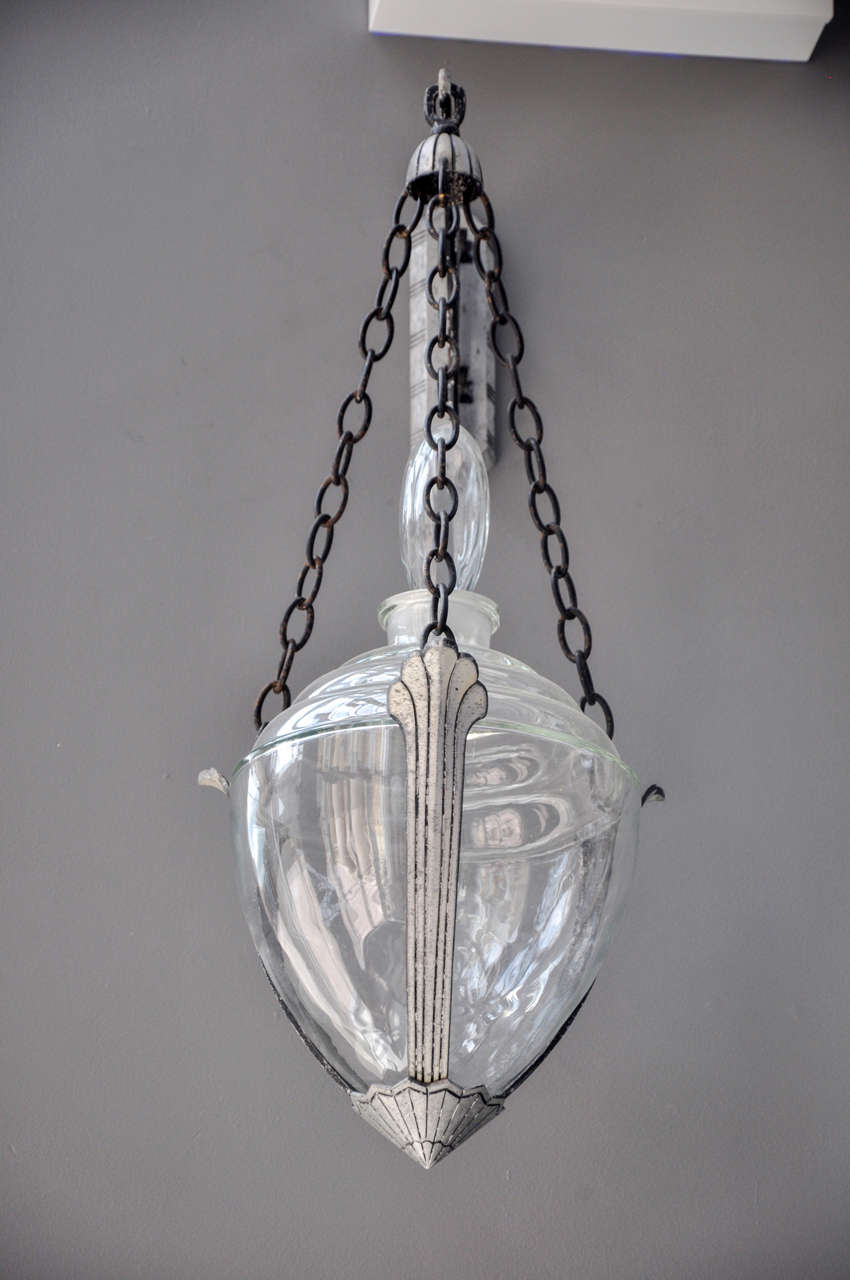 A pair of Art Deco drug store glass globes with stoppers, hanging from three chains on a highly decorative hook.