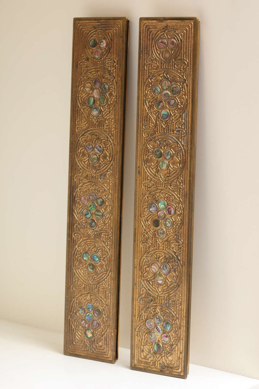 These early 20th century antique bronze blotter ends are elaborate and beautiful. Amongst the linear designs engraved in the bronze are abalone gemstone discs. The blotters are signed “Tiffany Studios, New York, 1153” on the bottom.