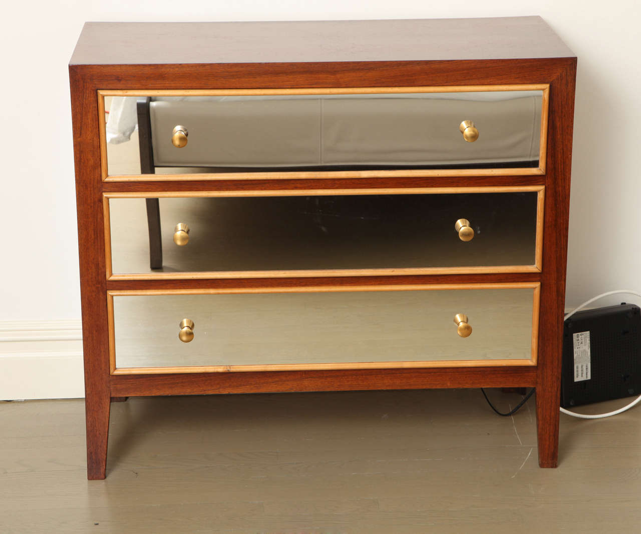 Maple chest of drawers with brass and mirror details.