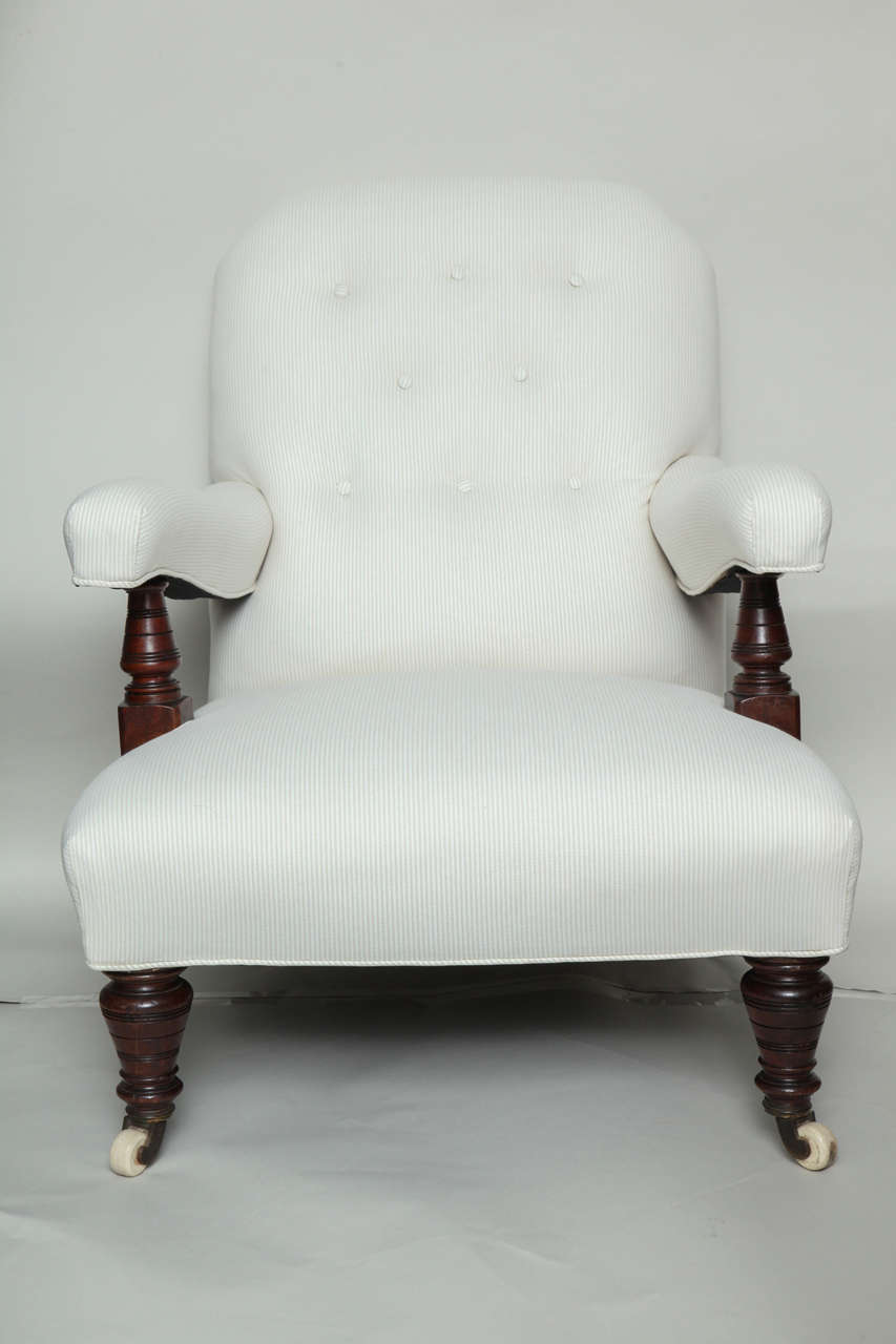Good late 19th Century English open arm club chair, the shaped back with shallow button tufting, the shaped seat with conforming arms having turned mahogany supports, turned front legs and shaped rear legs, all with original ceramic and brass