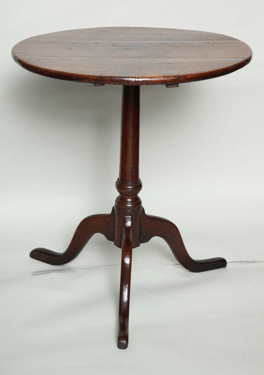 Good English oak candle stand, having a circular top with rounded edge, standing over a central shaft with suppressed ball turning, standing on slipper feet, the whole with excellent color and patina and retaining original blacksmith made iron