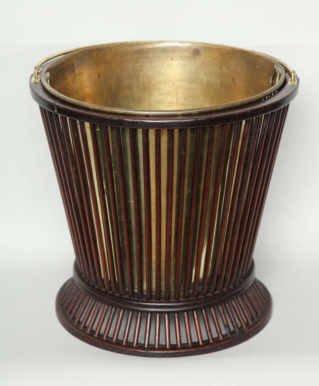 Unusual Georgian mahogany peat bucket with brass bail handle and liner, the rim, waist and base turned from the solid, the tapered body and flared base entirely made from turned mahogany rods, the whole with good color.
Perfect as a waste paper