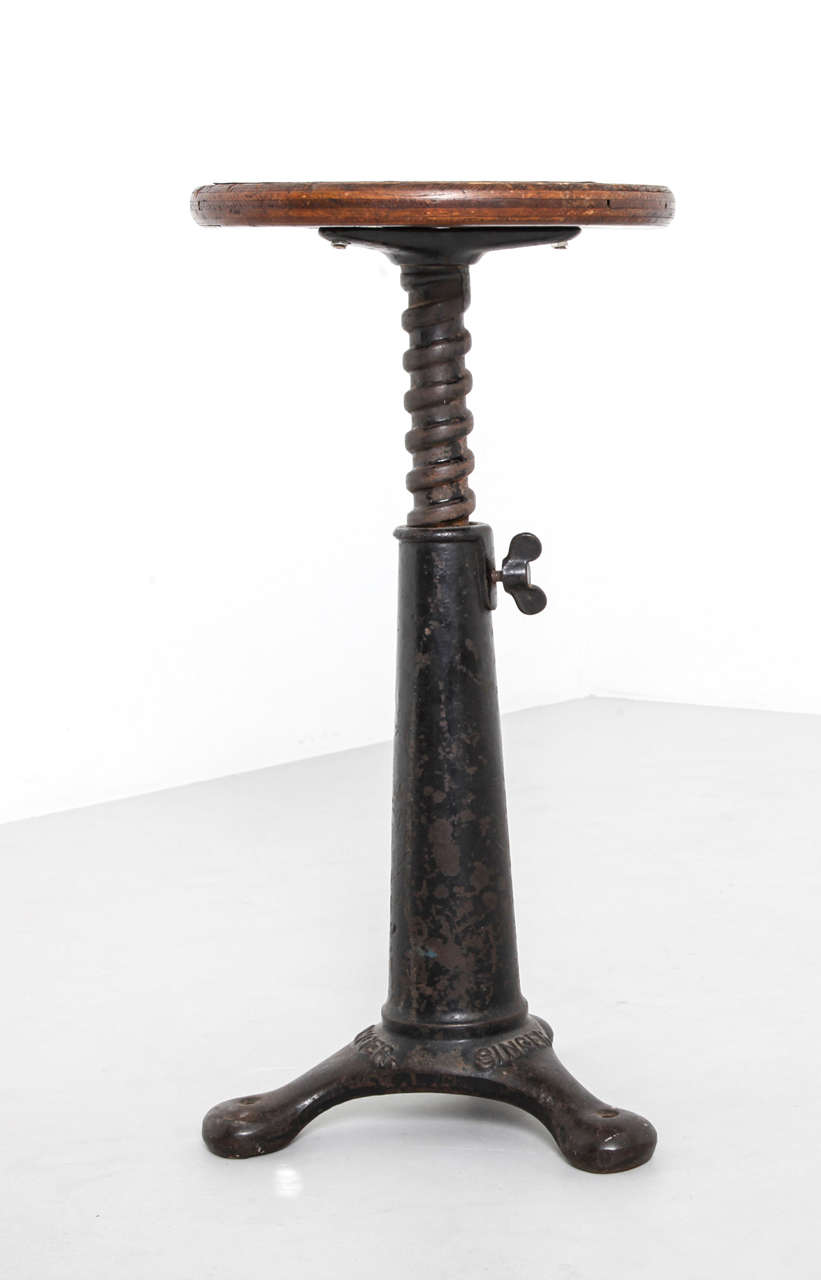 Singer Stool from a French factory. 
Heavy duty cast iron adjustable bases with nicely curved seat. The seat corkscrew into the base and have a large wing nut securing them in place.45/50 cm