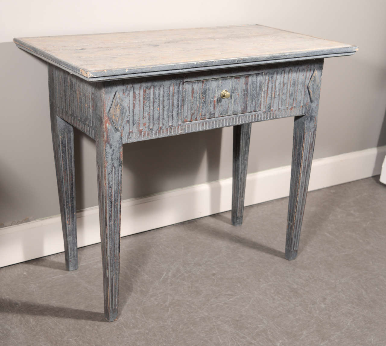 Side table with deep overhang. One-drawer. Oxidized dark blue paint, with lighter, worn gray paint on top. Carved reeding characteristic of the Louis XVI period as interpreted by King Gustav, circa 1860.