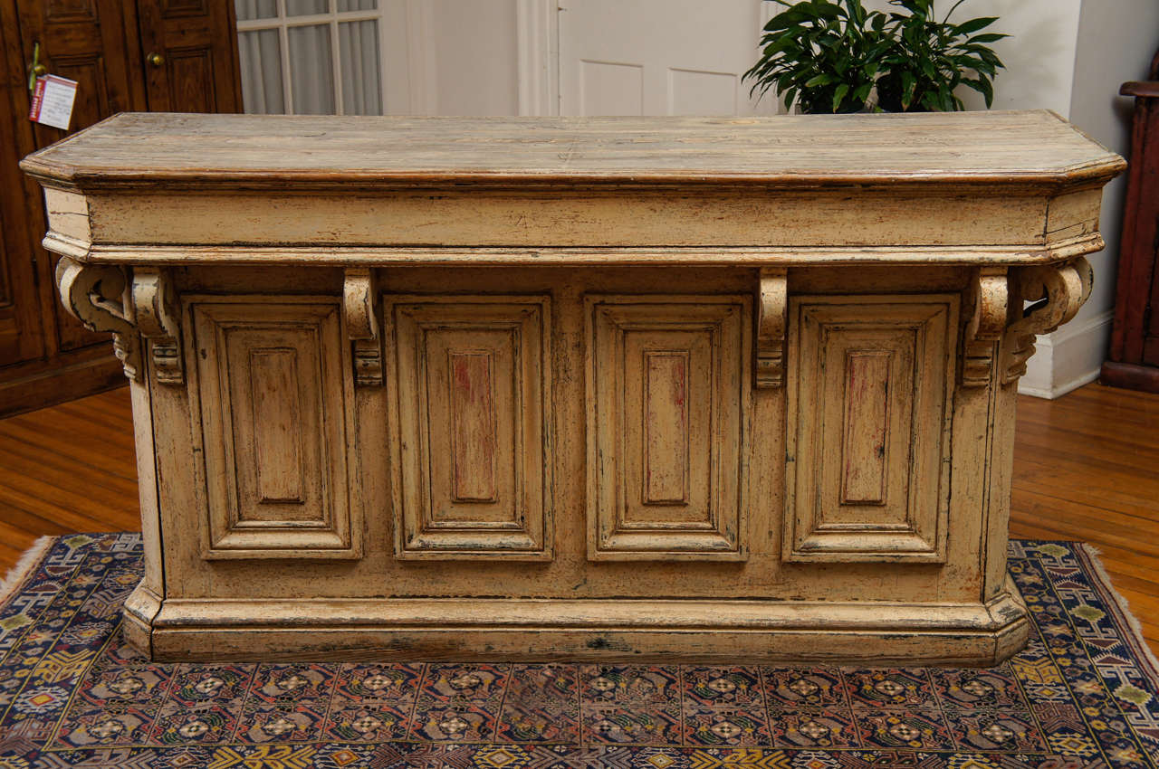 Here is a wonderful old French store counter that you could build a kitchen around. This 1860 piece has graceful corbels on the front and both ends along with large multi paneled designs. The backside has one drawer at the top, a storage area is