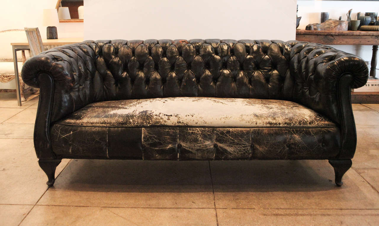 The wear on the seat only adds to the beauty of this perfect black leather Chesterfield sofa. Completely useable with no cracking, repairs or shedding of leather.