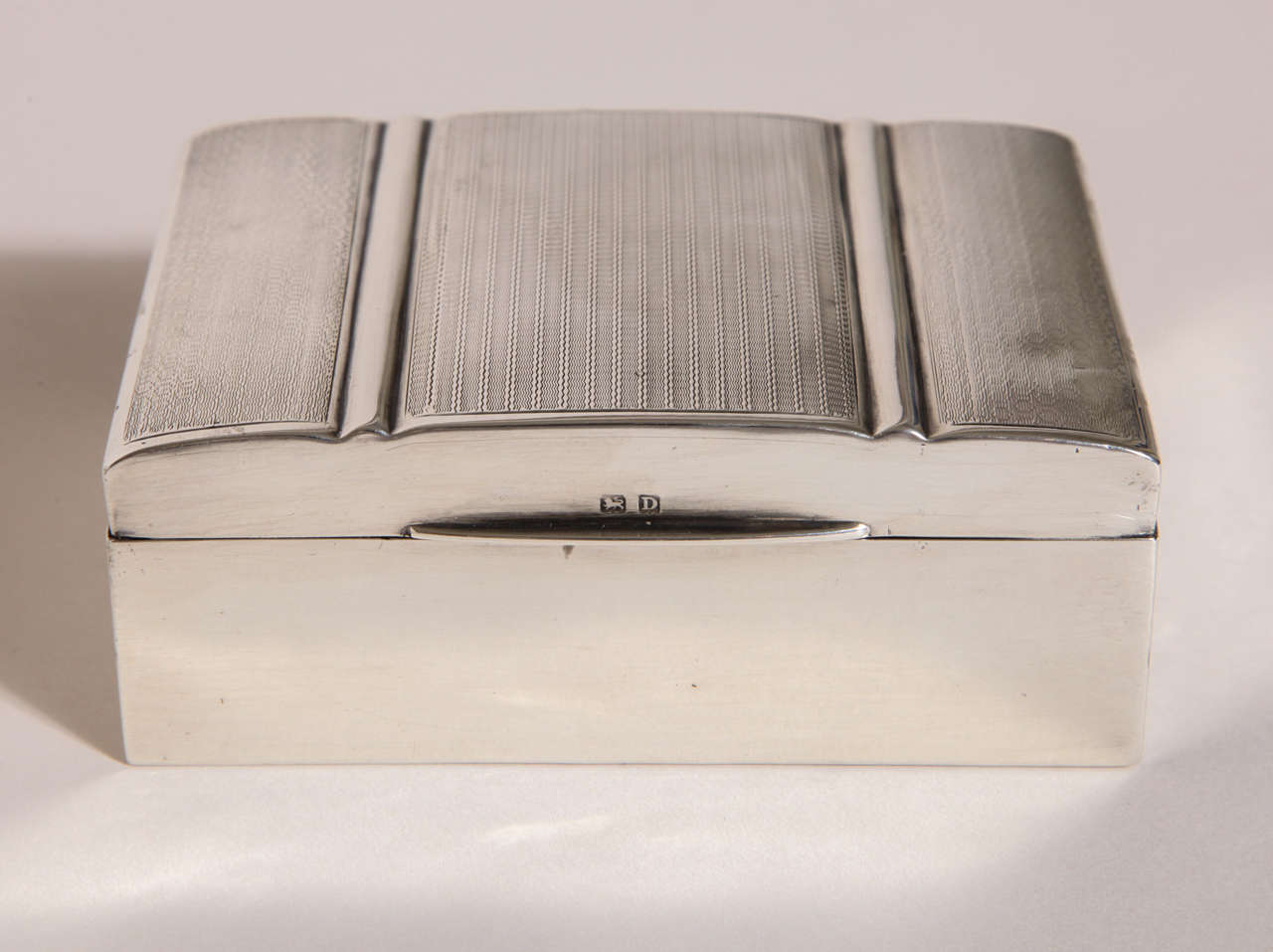 Sterling silver box with stylized Art Deco top with three sections decorated with engine-turned engraving and with cedar-lined interior.
Hallmarked for 925 silver/ Birmingham/ 1928/ HM.

12.15 ozs. gross.