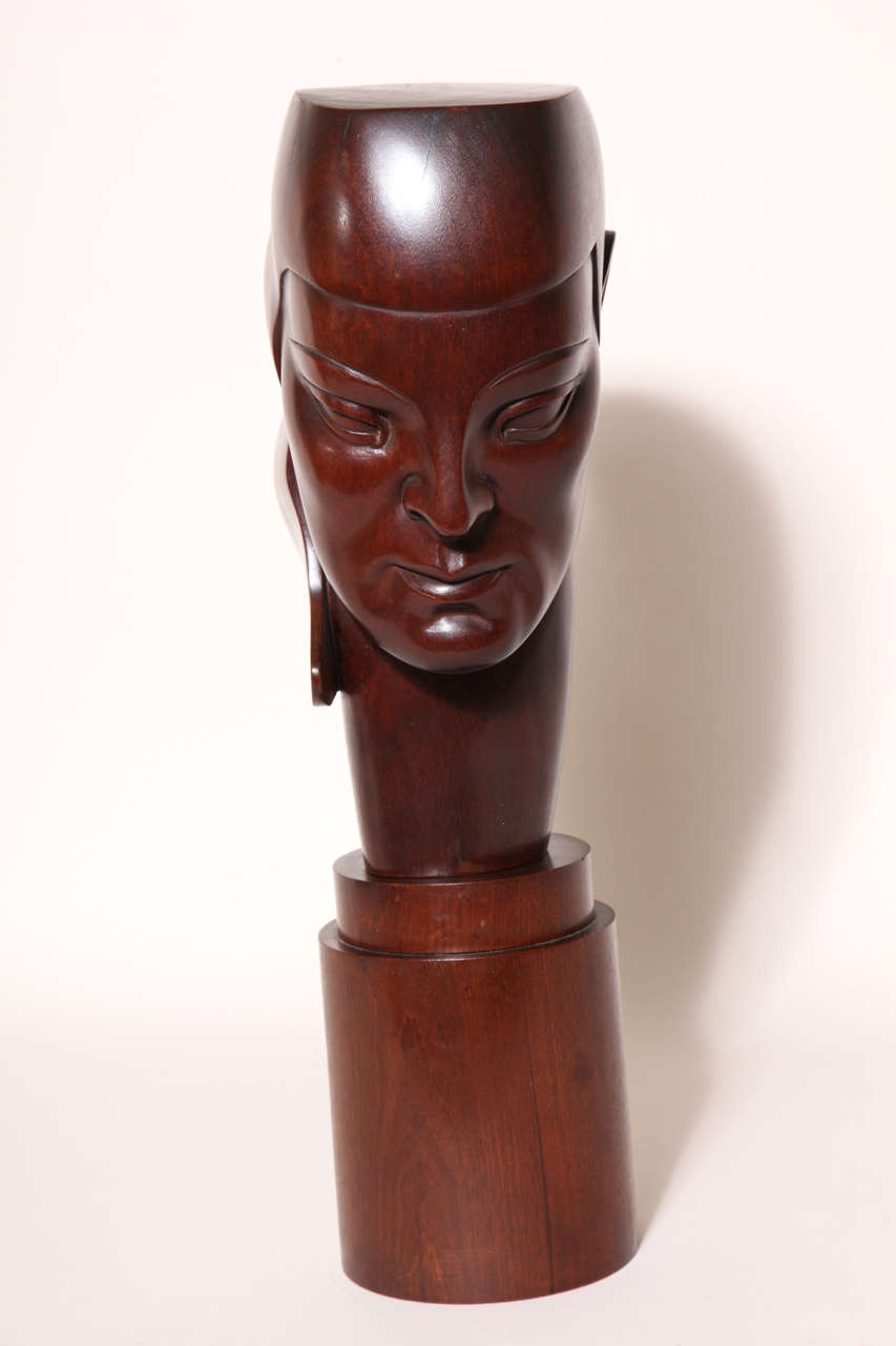 This wood sculpture of a downward looking head wearing a hat with flaps has a triangular wing coming off the rear. It is mounted on a cylindrical base. Konolei is an American, who worked in Paris in the 1930s.

Inscribed Manya