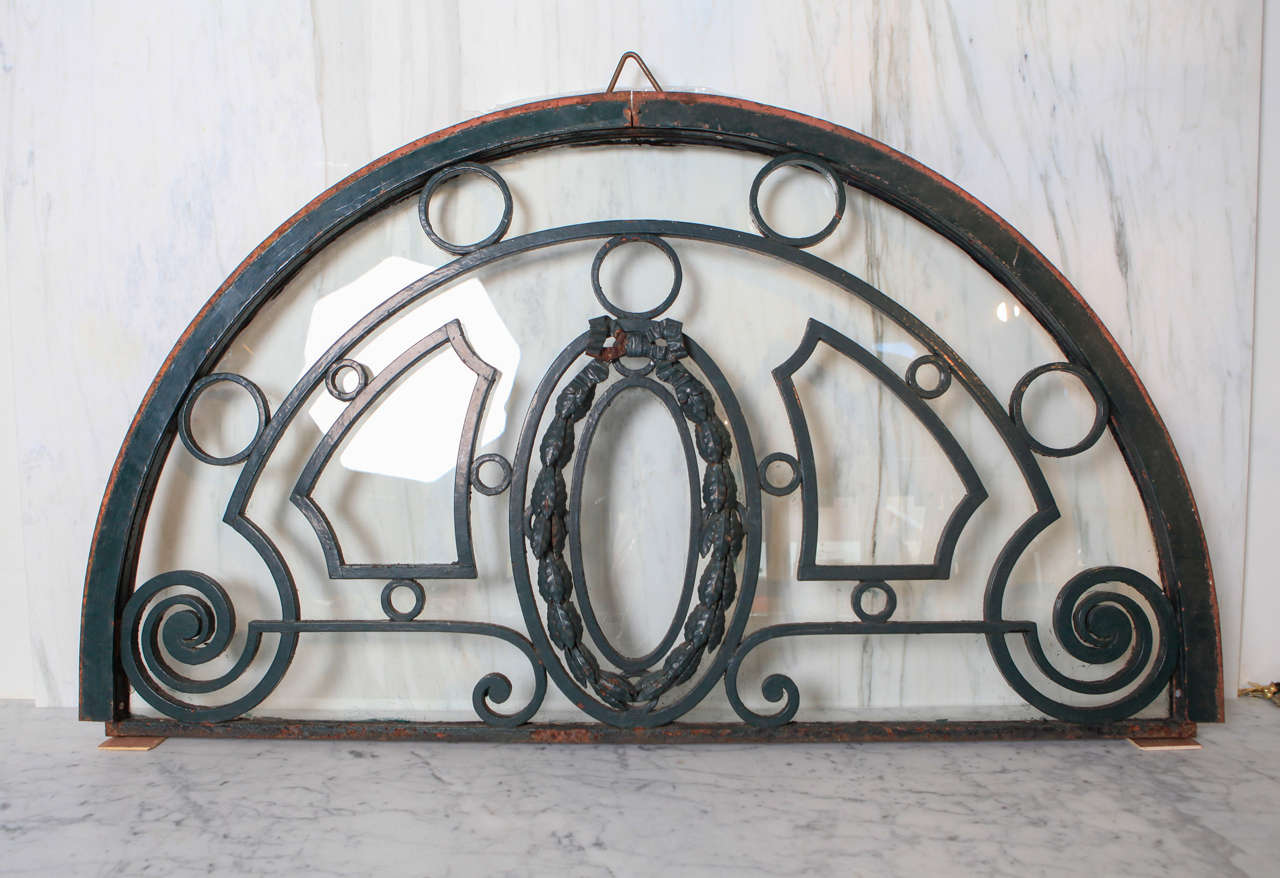 Semi-elliptical iron transom window has ribbon and leaf motif painted green.  One single glass back panel, which can be removed.