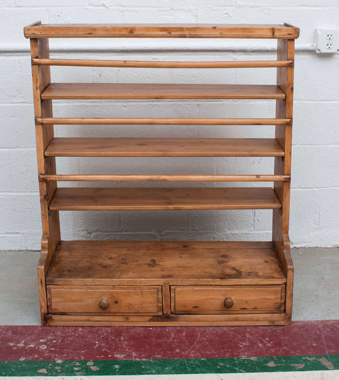 A charming two-drawer hanging plate rack featuring all morticed and dovetailed construction with four shelves for storing or displaying small plates or other objects.