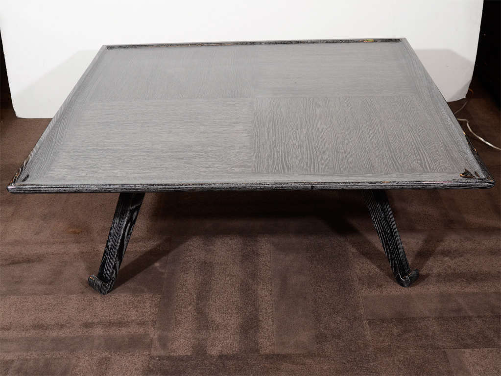 Outstanding cocktail table with modernist design in silver cerused oak finish.
The table has a large square top with recessed borders patchwork top design.  Another feature is the beautiful stylized scrolled legs with splayed design. 
This is a