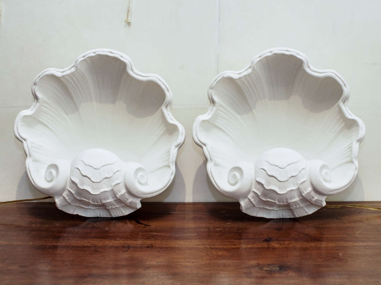 A pair of white plaster of paris wall sconces in a sea shell motif.
