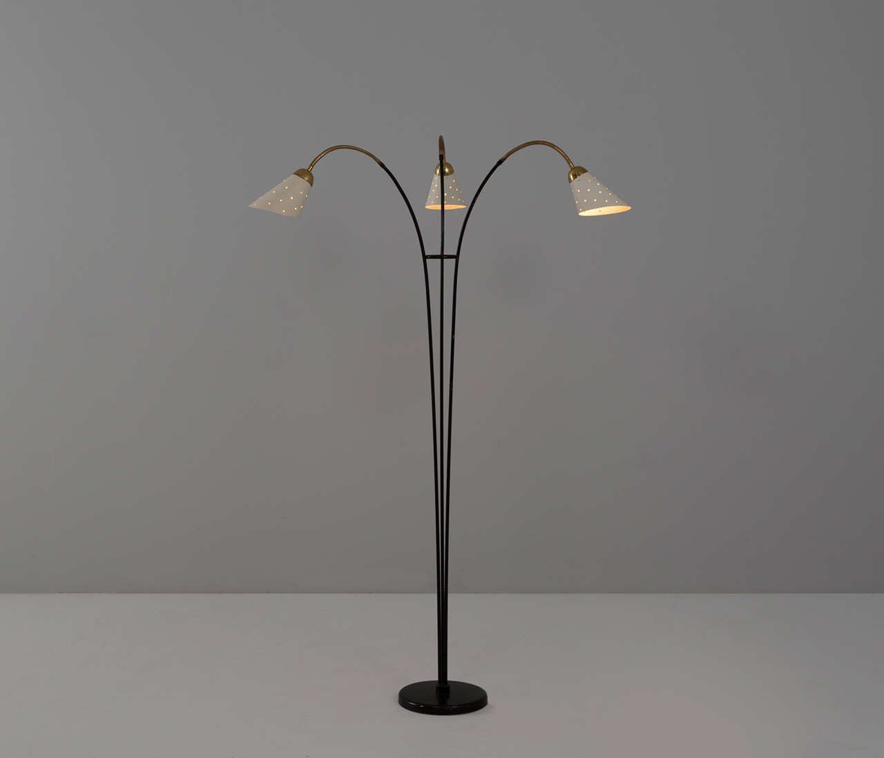 Adjustable italian floor lamp with elegant brass details. The base is made of black coated steel.

The shade are off white lacquered, and due the perforated pattern a nice light partition is created.
