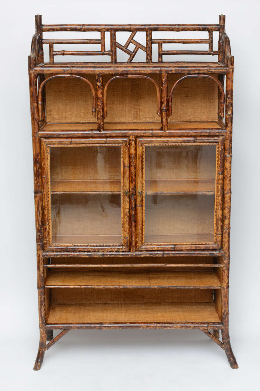 Very handsome antique bamboo cabinet with original handblown glass doors.  Sides and all shelves lined with raffia.