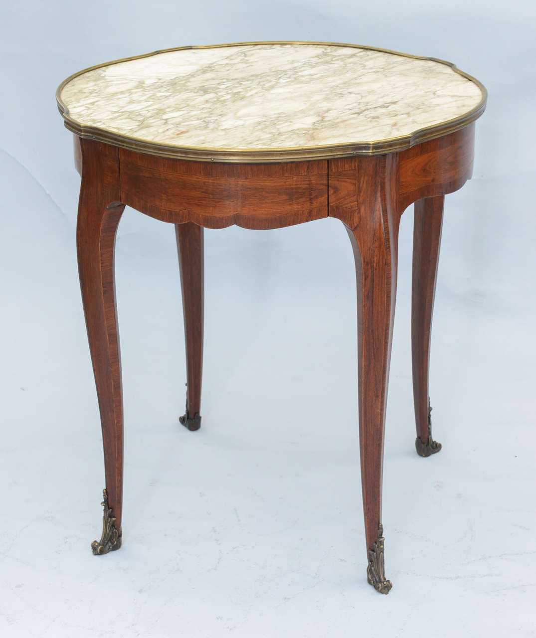 Accent table, of walnut, having veined marble top inset in raised bronze frame, single frieze drawer, raised on cabriole legs terminating in bronze scrolling acanthus feet.  Label in drawer:  