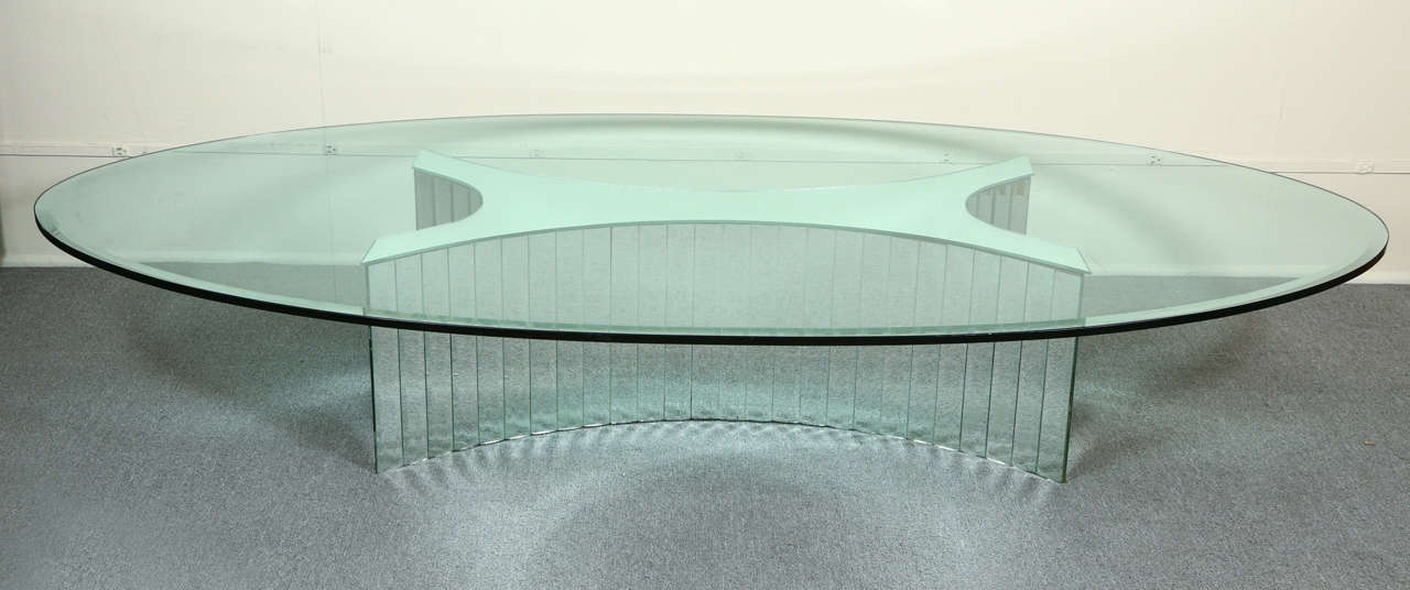 Fabulous oval coffee table with a glamorous mirrored base and glass top.
The sides of the base are covered with vertical strips of beveled mirror, and the large 3/4