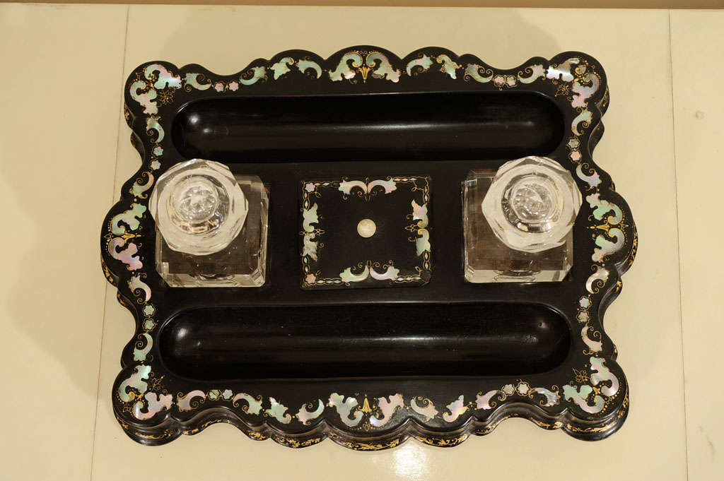 Fine mid-19th century inkwell with inlaid mother-of-pearl decoration surrounding pen trays, a lidded compartment and two crystal inkwells. The whole raised atop four flattened bun feet.