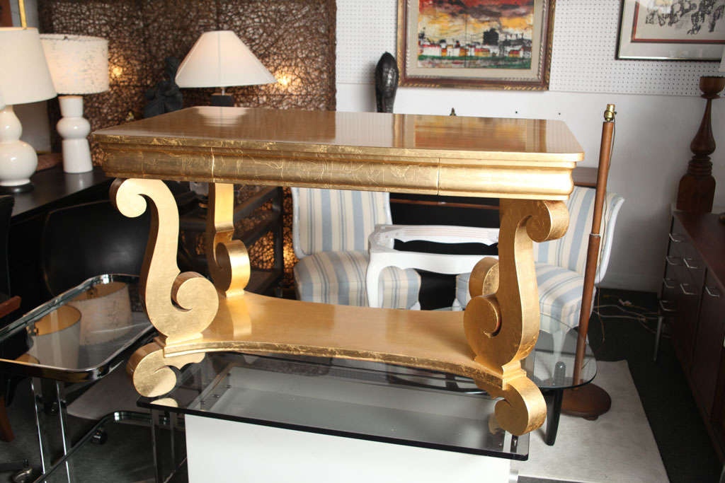 Gold leafed console desk table, a real bold decorator item, in a dark room or hall with the right lighting.....