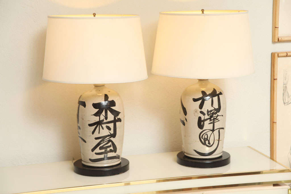 This wonderful pair of 19th C. sake jugs have beautiful hand-painted Japanese lettering all around. Converted to lamps in the late 1940's, we've retained the original socket casings with all-new electricals. (Shades not included.)