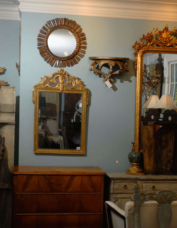 A French gilded and painted wooden mirror from the 19th century. This French mirror from the late 19th century features a rectangular frame decorated with moldings of various motifs and topped with an exquisitely carved crest. The gilded roses, urn,