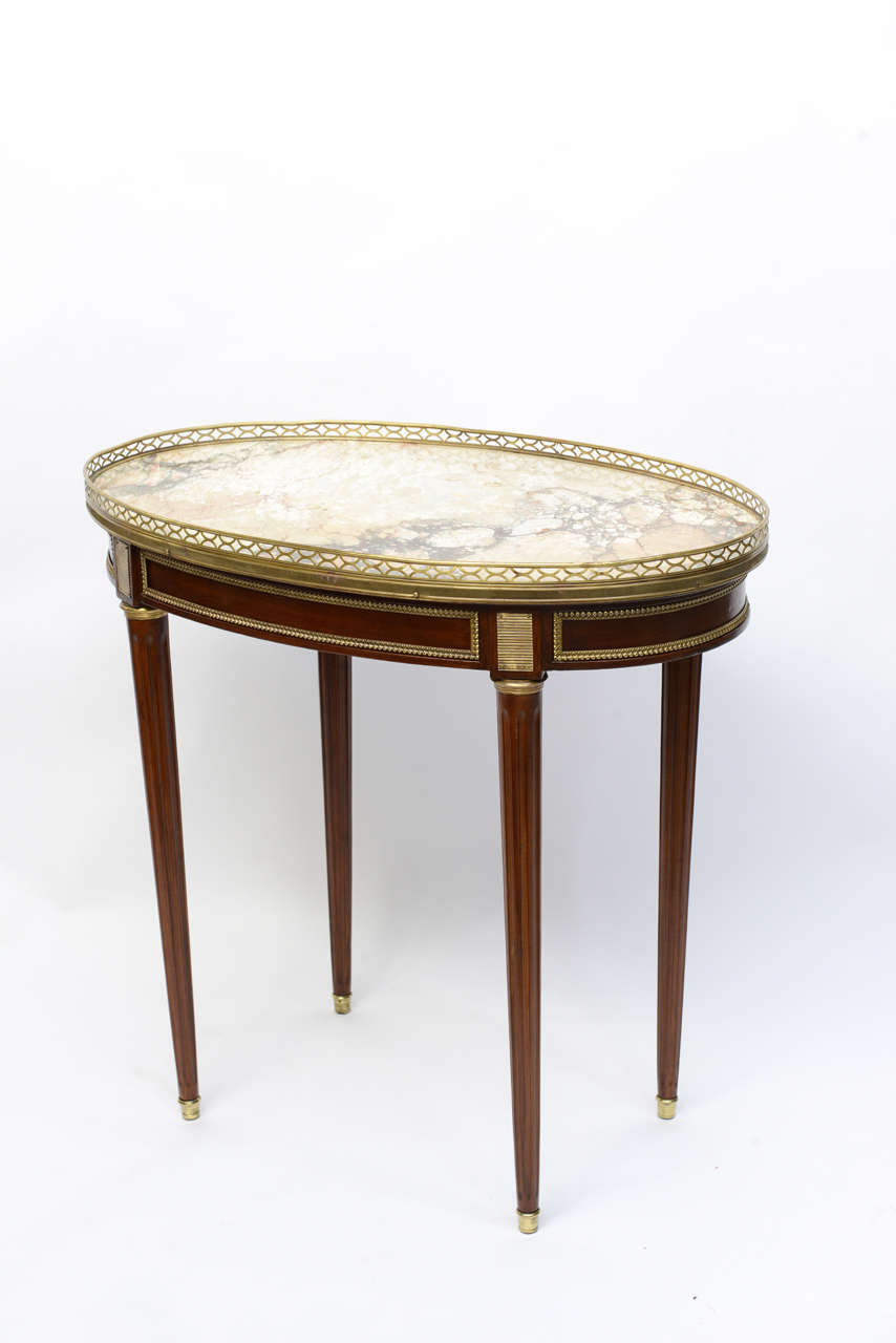 Exquisite 19th century oval bouillotte table with striking taupe/grey marble top and decorative mounts.