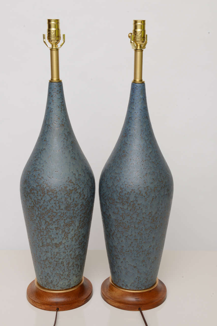 ...SOLD...Great scale with this pair of tall teak based lamps with teardrop vase form of mottled blue & fawn lava drip glaze.  Beautifully created with solid brass mounts, necks & sockets.  Just add your shades!

Completely rewired, New UL brass