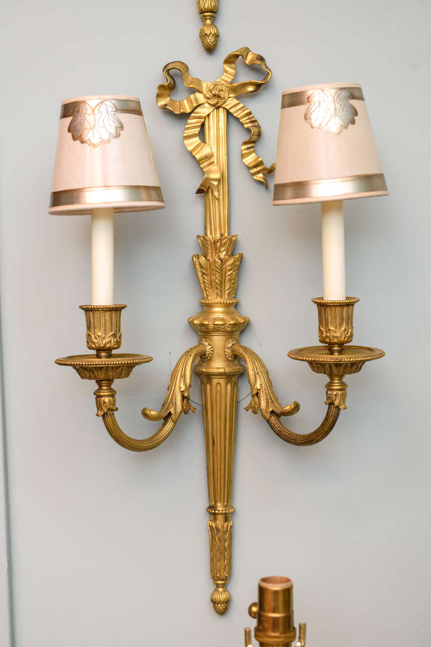 Set of four gilt bronze ribbon and grooved center with arrow feathers, two-branch sconces stamped by E.F. Caldwell, circa 1900.