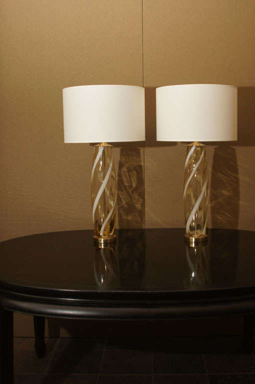Cylindrical pair of murano glass lamps with candy stripes of yellow and white mounted on polished brass bases with double clusters and new paper shades.