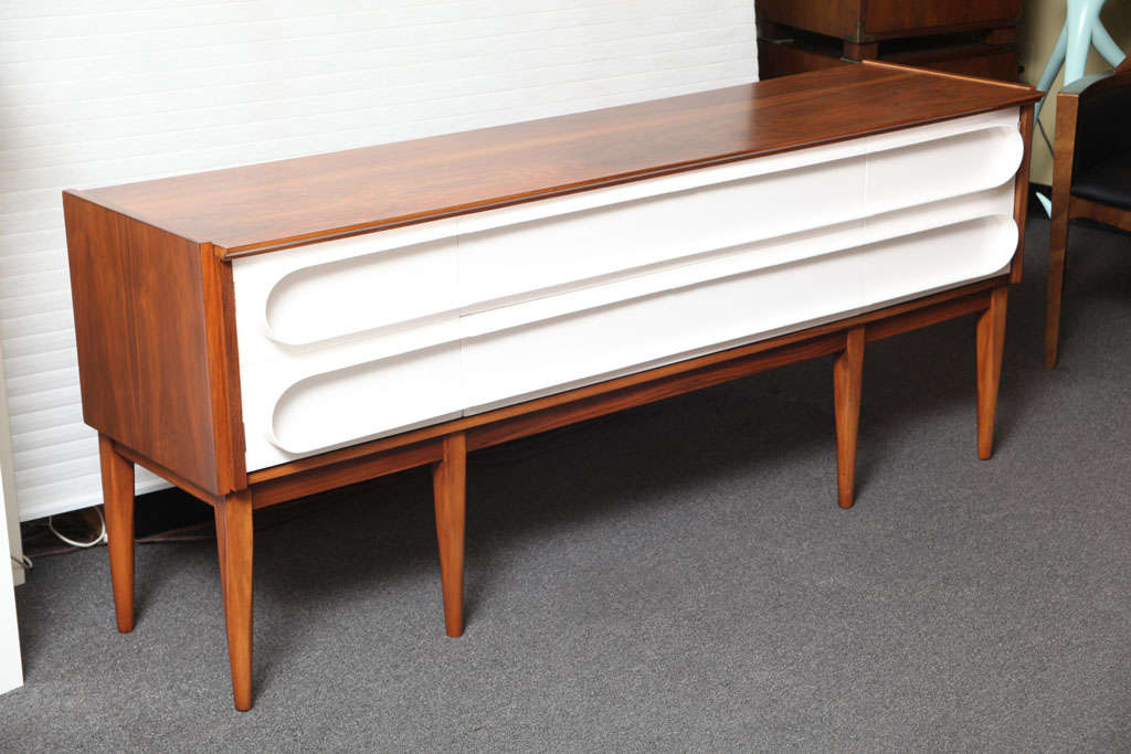 ...SOLD SEPTEMBER 2010....Spectacular modernist credenza in the manner of Ponti in gorgeous figured walnut and a white lacquered architectural sculpted front featuring two doors and two drawers.  Shaped overhanging top, fine tapering legs...a